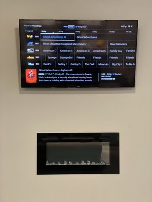 Premier TV Mounting Atl — mounted flat-panel TV stacked cleanly above a slim black electric fireplace on a white wall