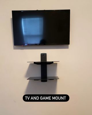 Premier TV Mounting Atl — wall-mounted TV paired with floating glass game-mount shelves below for console storage